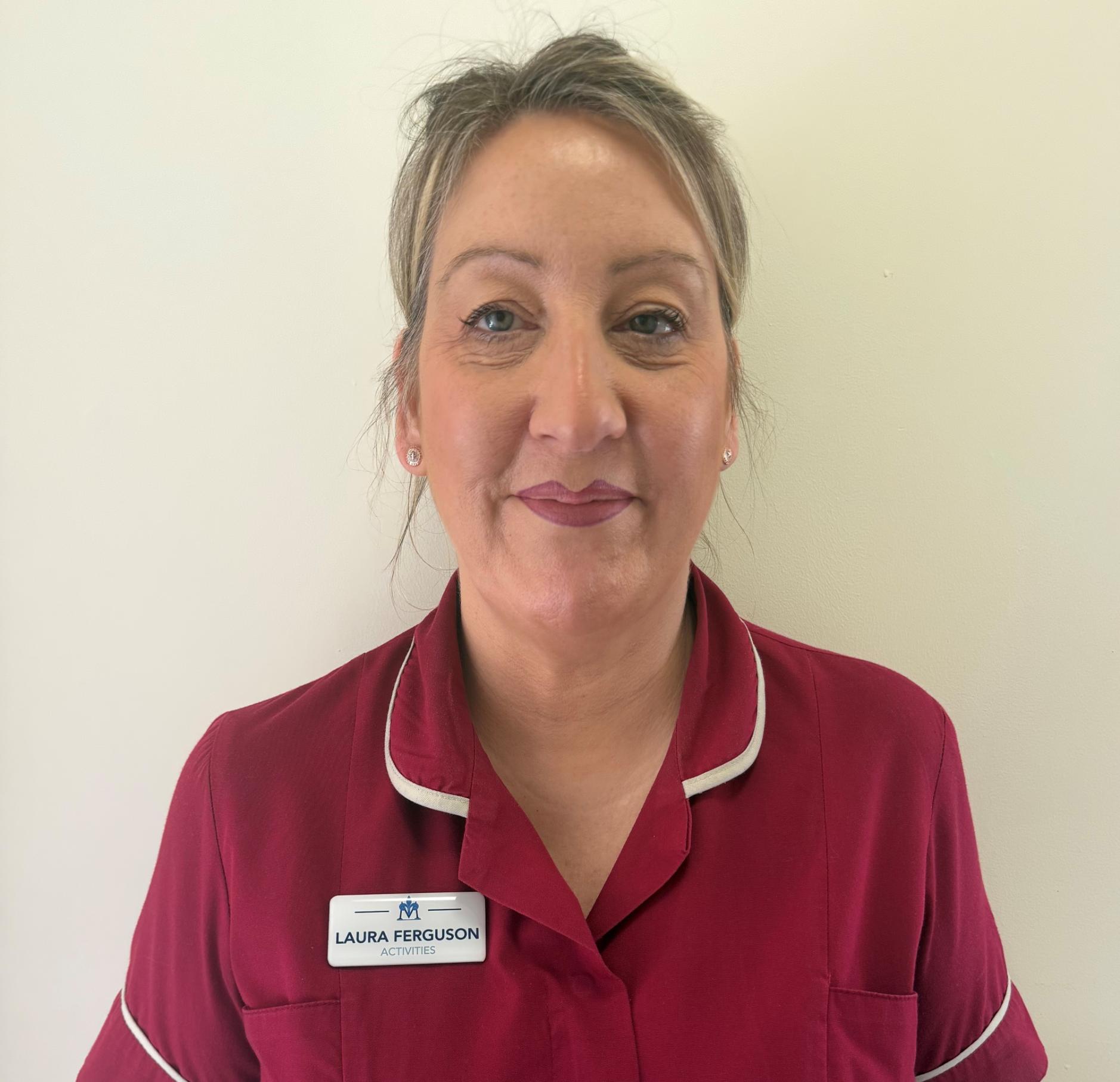 woman smiling in maroon nurses uniform