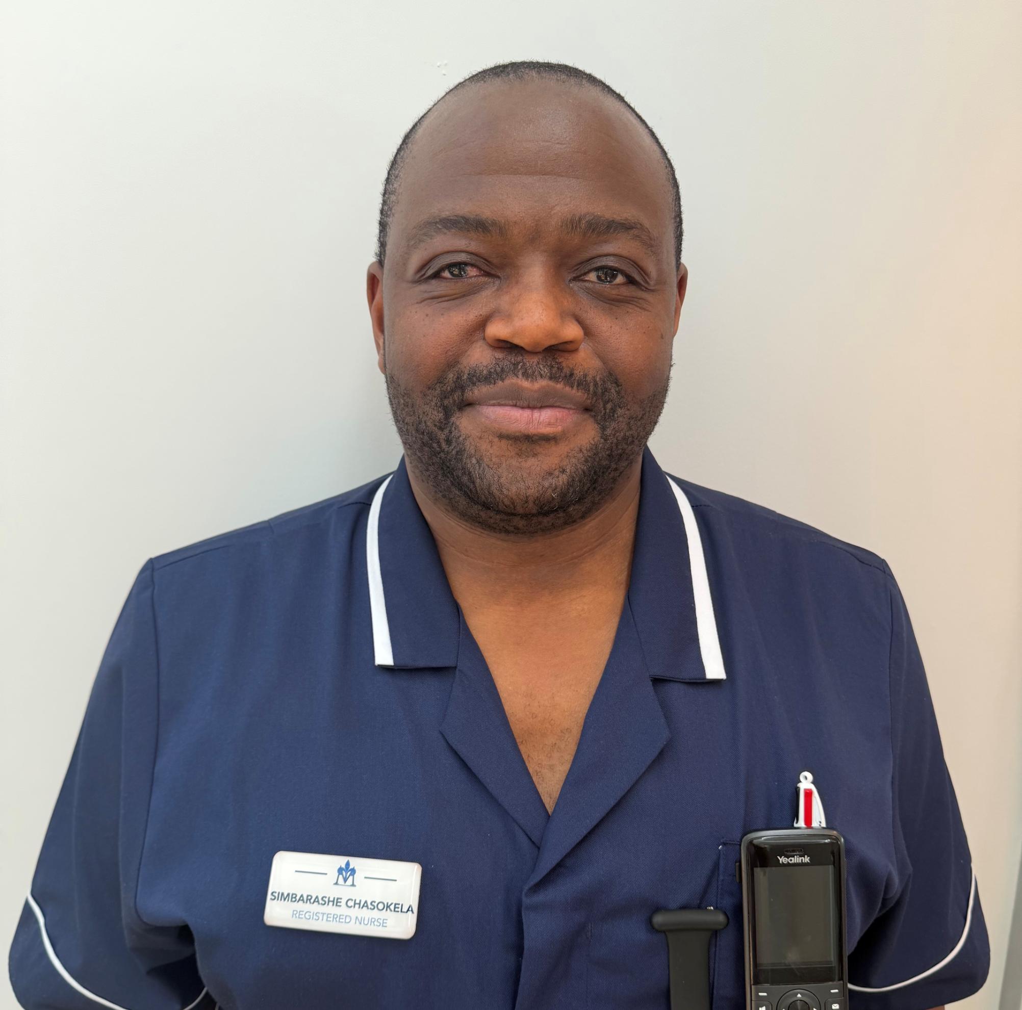 Smiling man in dark blue nurses uniform