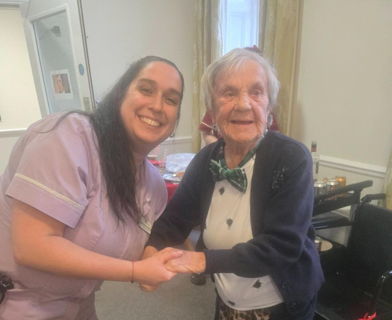 elderly resident dancing and smiling with nurse in lavender uniform