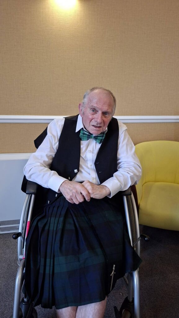 elderly man in wheelchair wearing a kilt