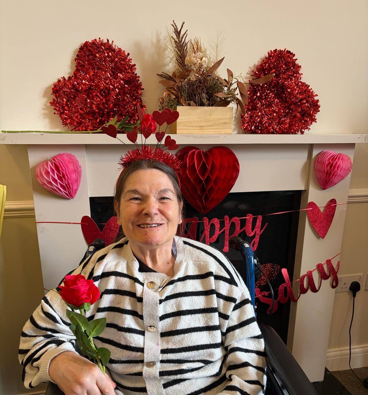elderly woman smiles surrounded by red and pink valentine's day decorations