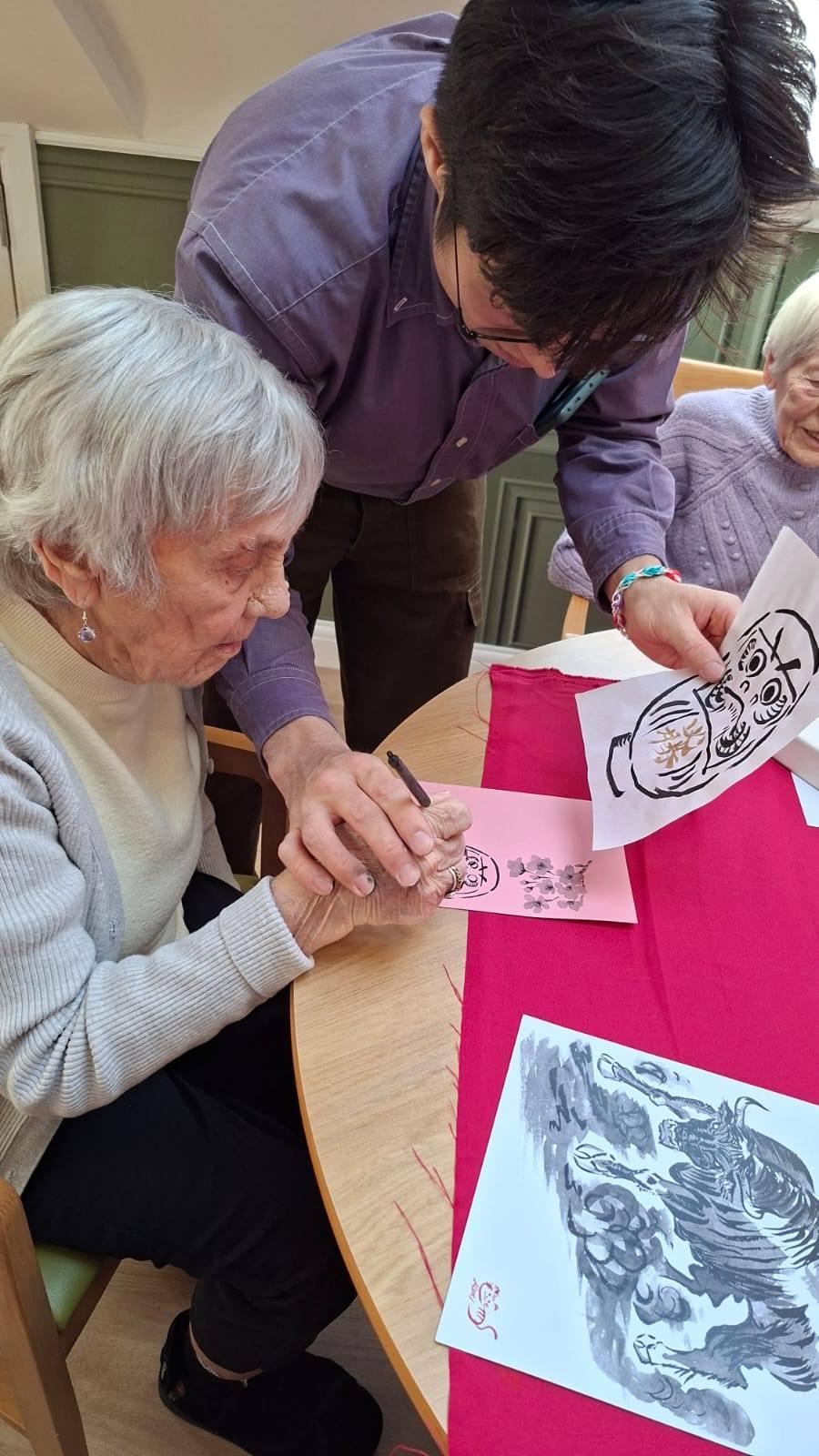 resident receiving help in a Japanese calligraphy workshop