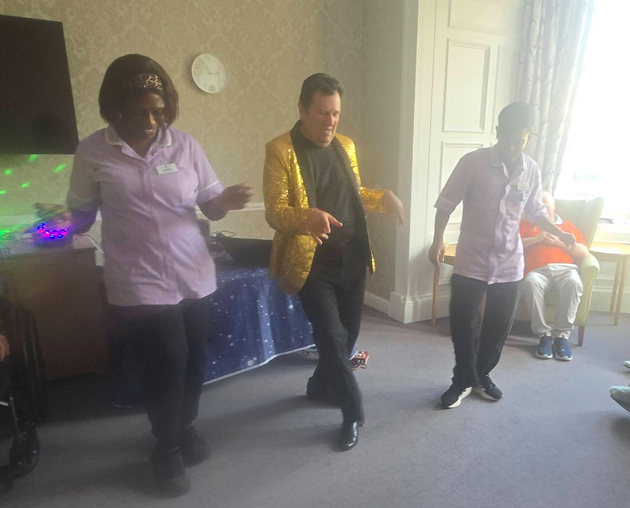 staff dancing with entertainer in glittery suit