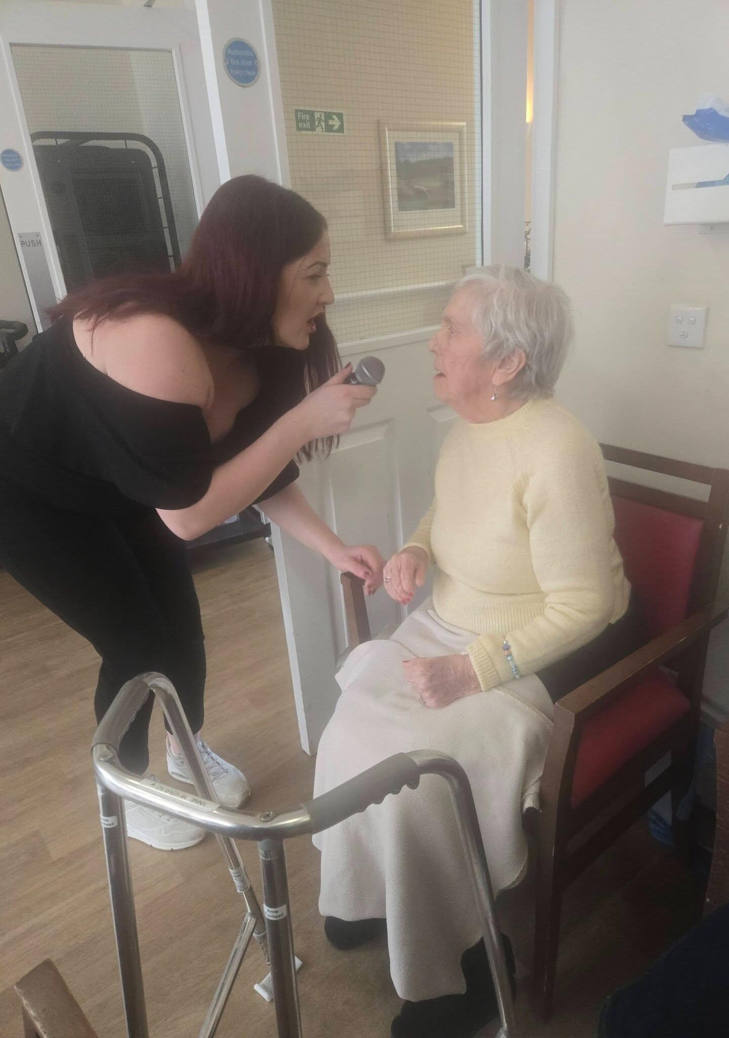singer holding microphone singing with elderly care home resident