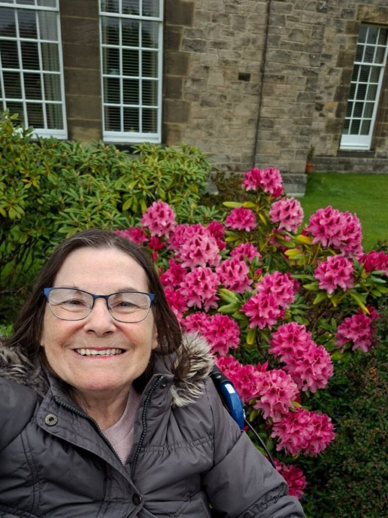 older lady sat in a wheelchair by some flowers