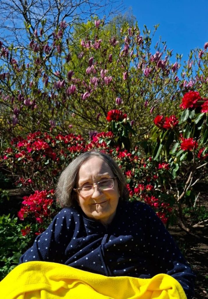 older lady sat in a wheelchair by some flowers