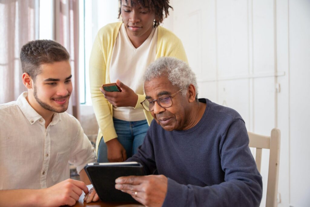 younger man helping older people use a tablet